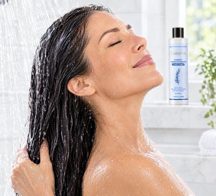 Woman rinsing conditioner out of smooth hair in the shower