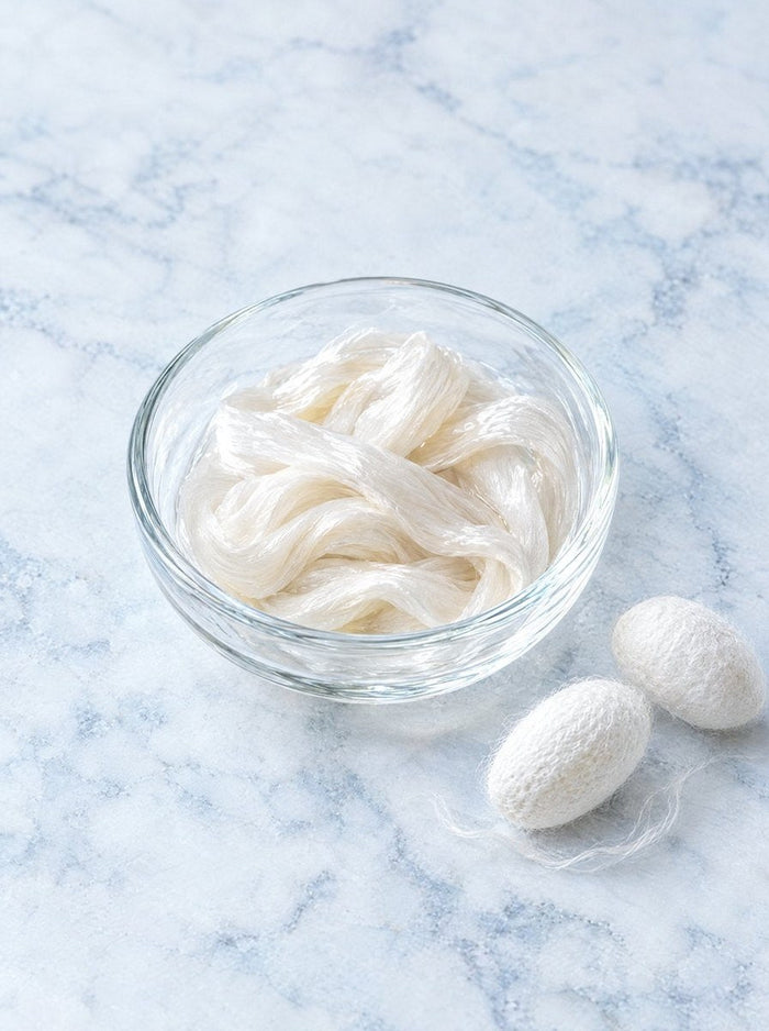 Silk fibres and cocoons in a glass dish
